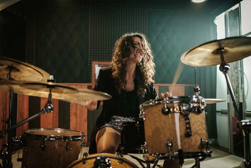 Woman playing a drum kit in a rehearsal room