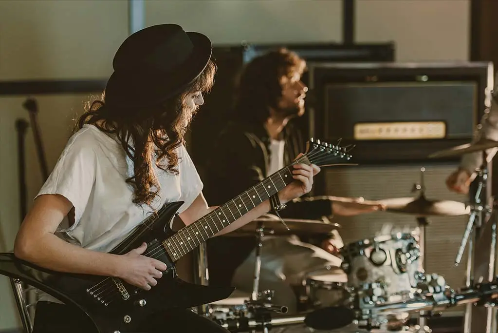 Woman playing guitar and man playing drums
