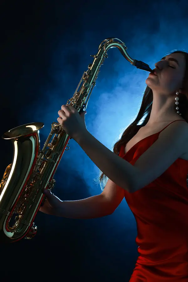 Woman in a red dress playing a saxophone against blue light