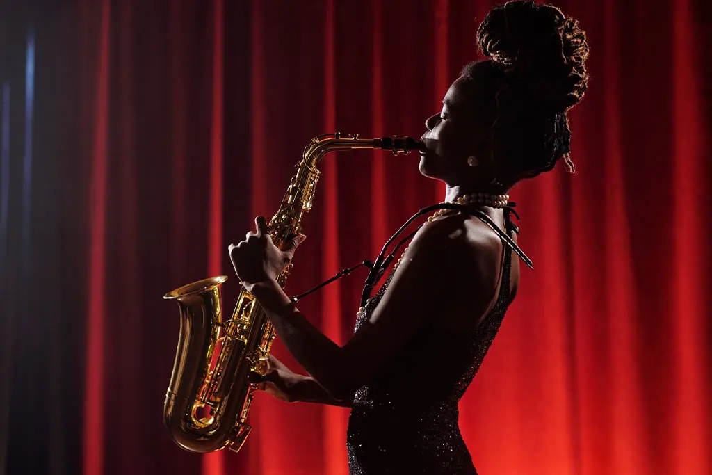 Woman playing saxophone in front of red curtains