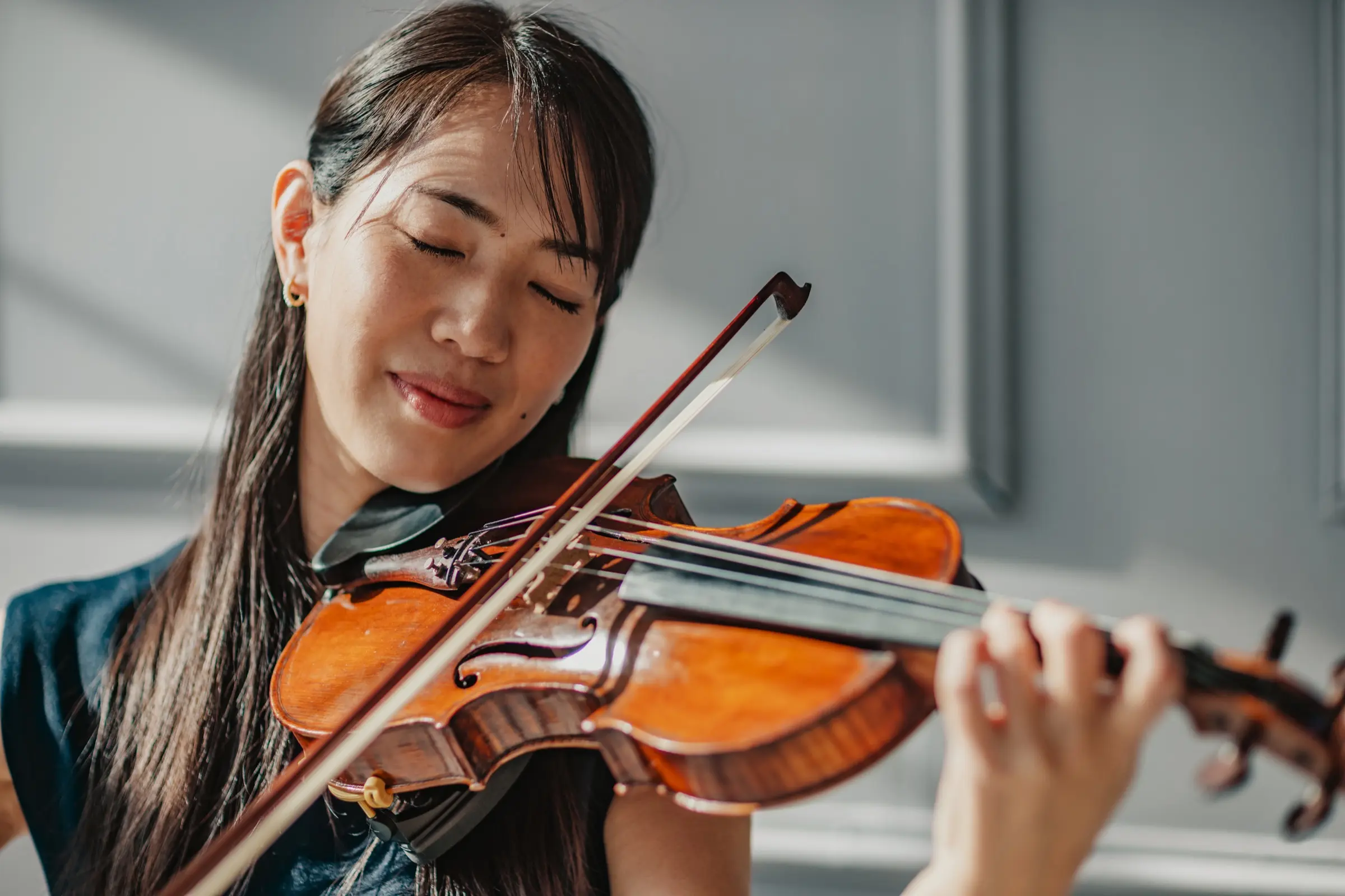 A woman playing the violin with her eyes closed