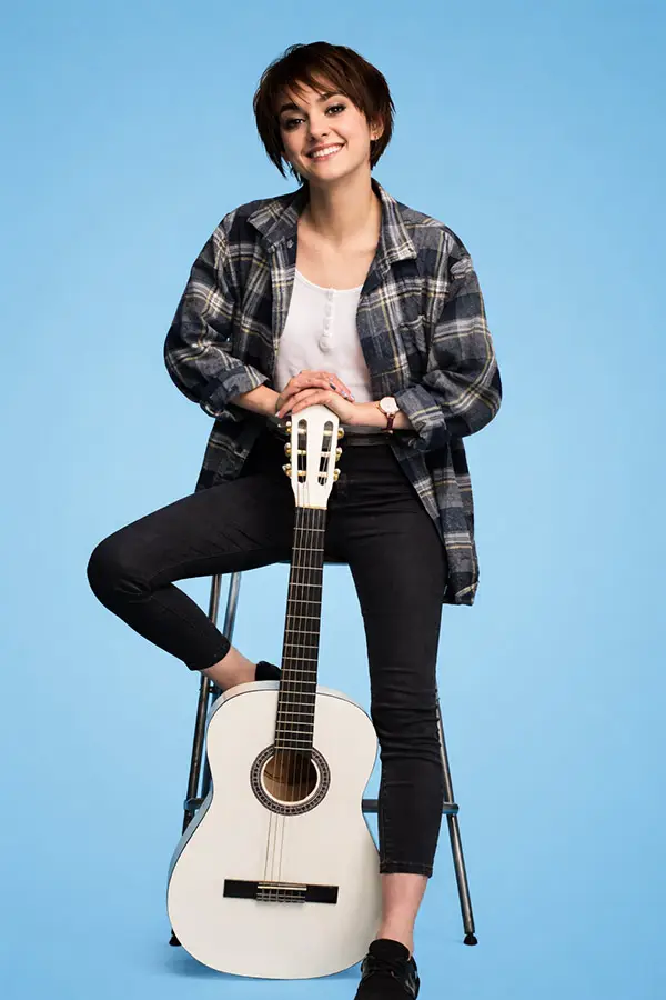 Woman on a stool with a white classical guitar