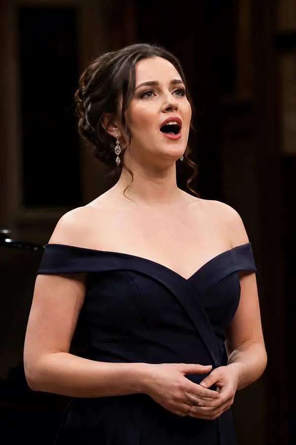 Woman singing in an off-shoulder navy dress on stage