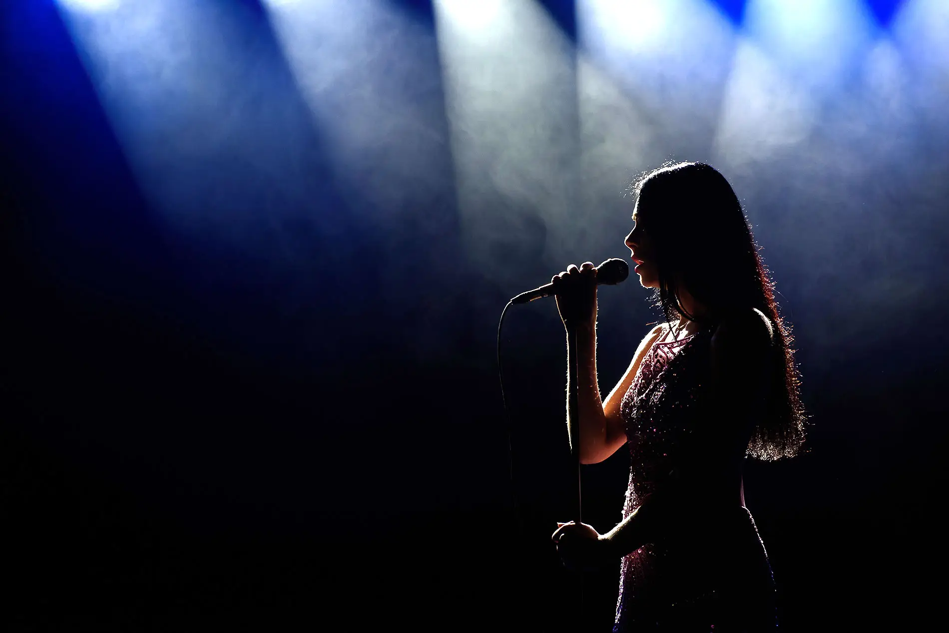 Woman singing on stage with background lights