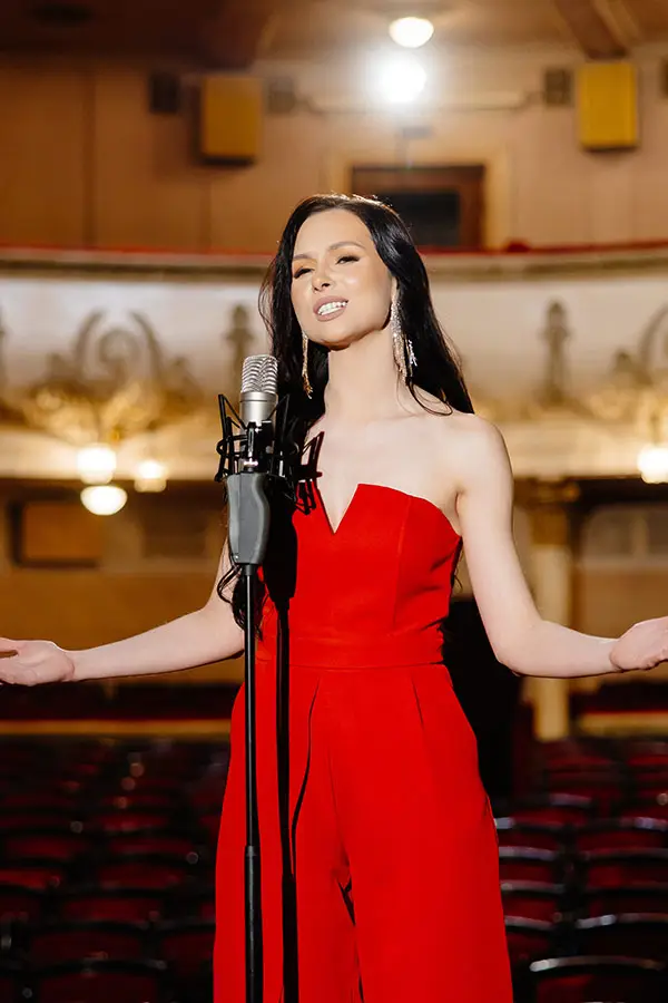 Woman in a red dress singing in a theatre auditorium