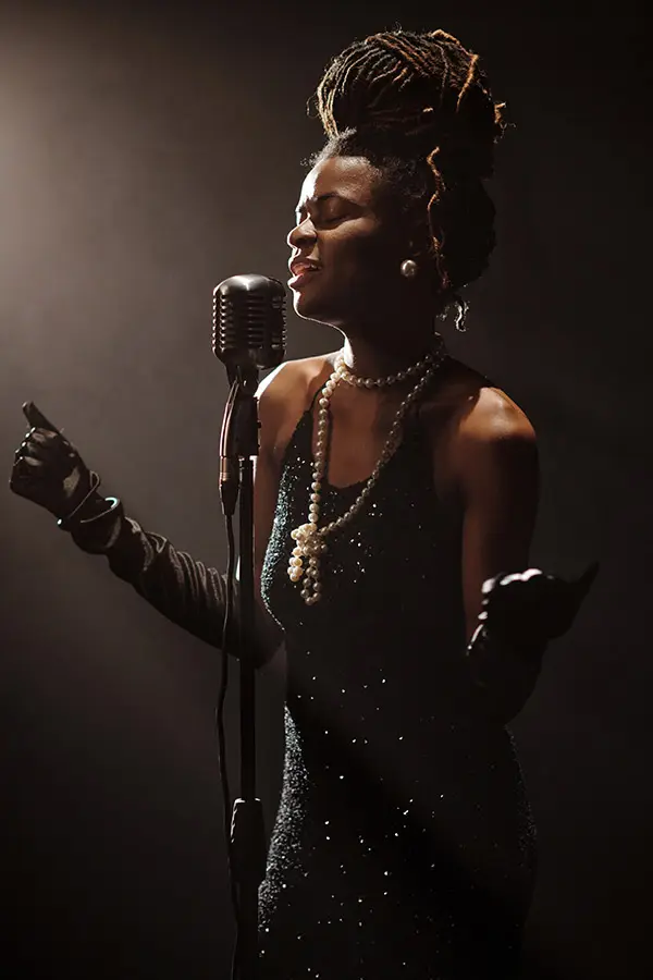 Woman singing into a vintage microphone under stage lighting