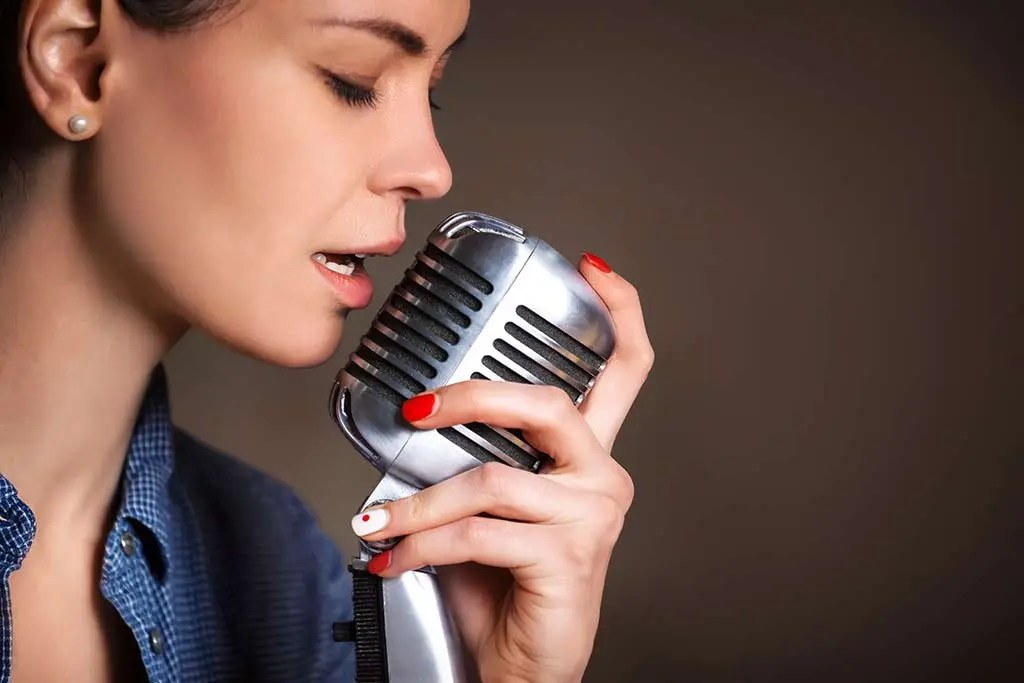 Close-up of a woman singing into a vintage-style microphone