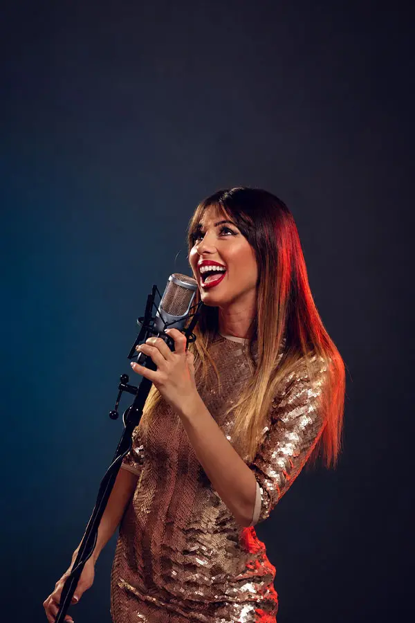 Woman in a gold sequinned dress singing into a vintage microphone