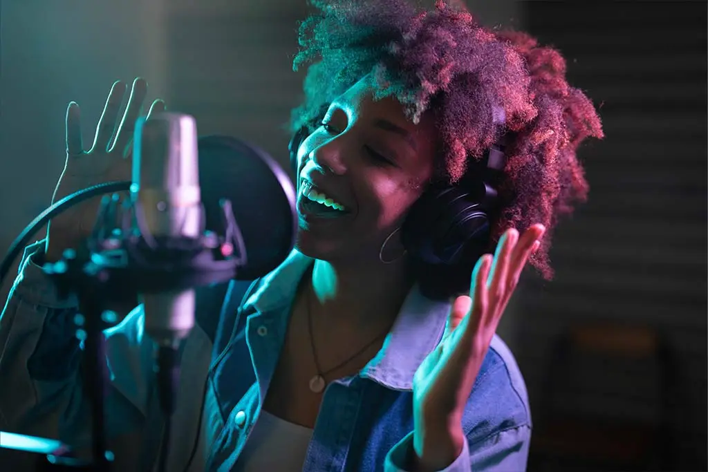 Woman singing into a studio microphone while wearing headphones