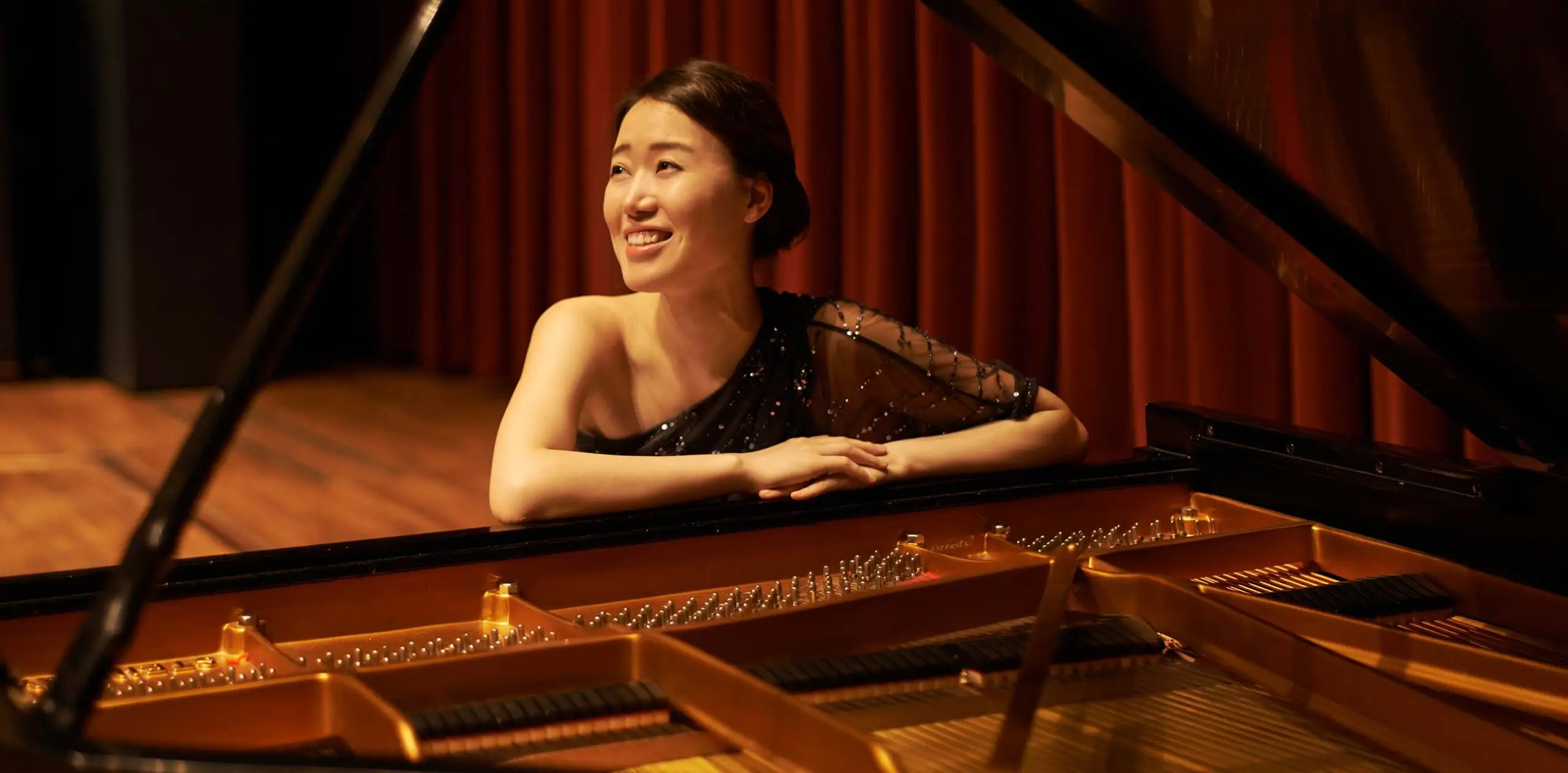 Pianist sitting at a grand piano on stage and smiling