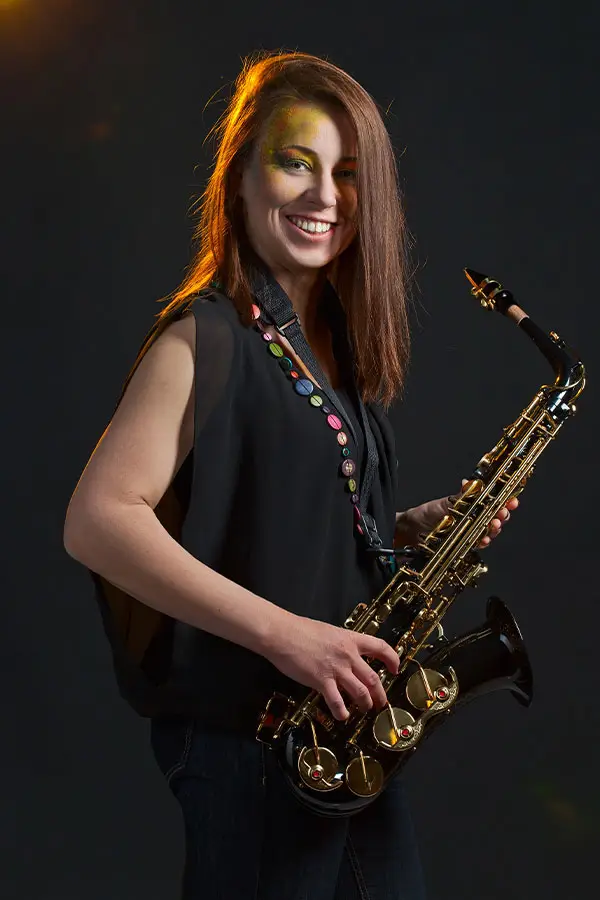 Woman smiling while holding a&nbsp;saxophone