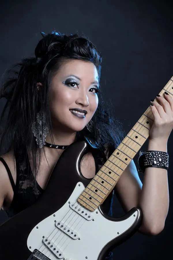 Woman with a studded wristband holding an electric guitar
