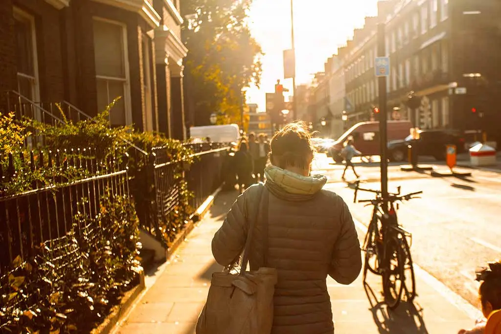 Woman walking along a sunlit city street