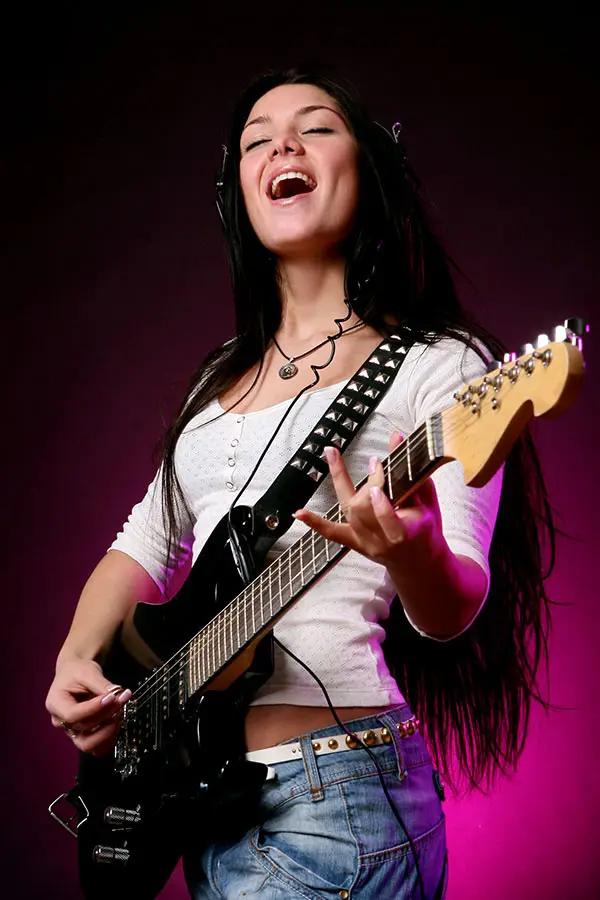 Woman wearing headphones playing an electric guitar