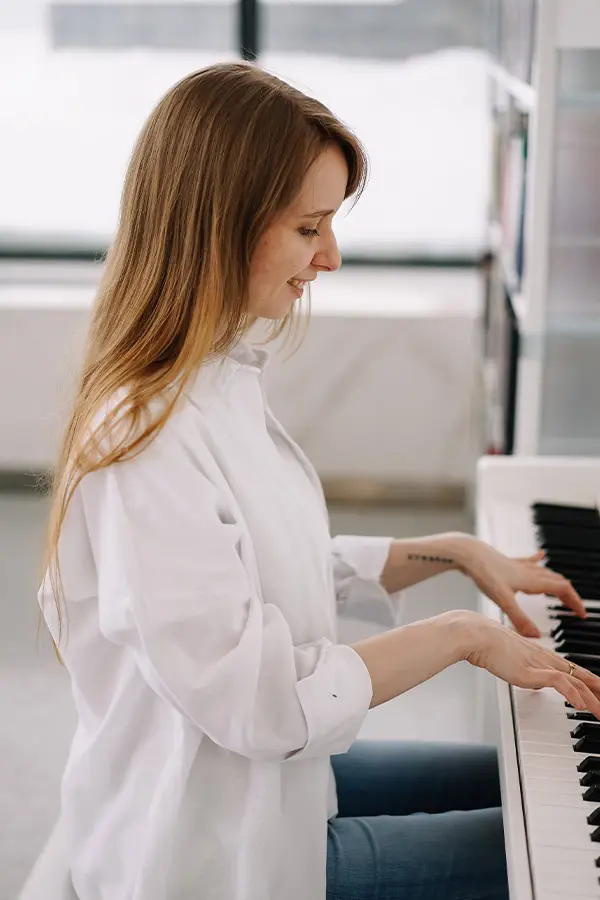Side view of a woman in a white shirt playing piano