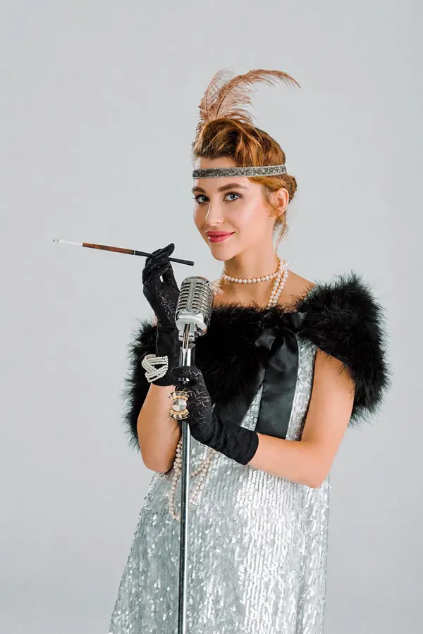 Woman in vintage costume holding a cigarette holder by a microphone