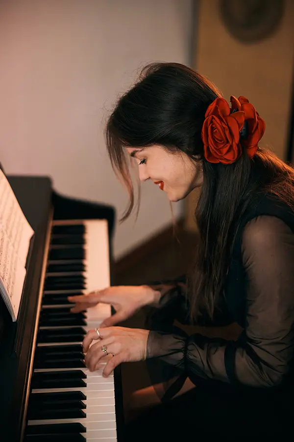 Woman with a red rose in her hair playing the piano