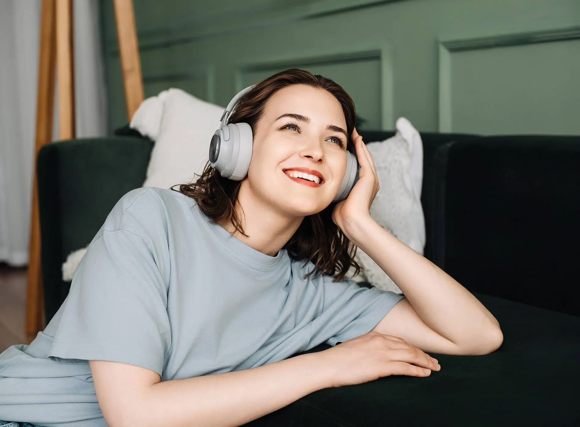 Woman relaxing on sofa with wireless headphones on enjoying music