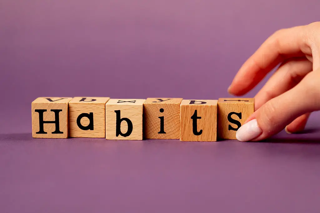 Hand touching wooden blocks spelling the word habits