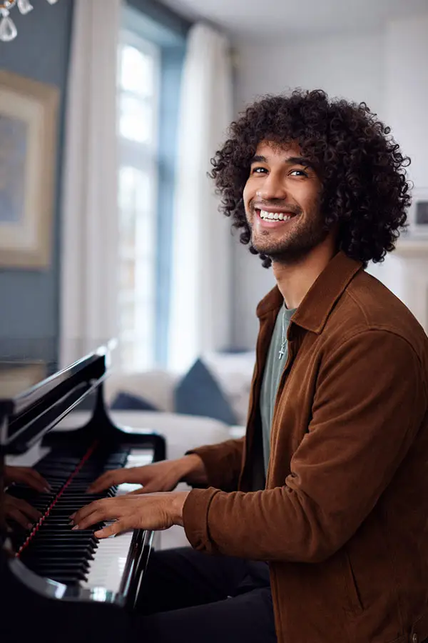 Smiling young man playing a grand piano