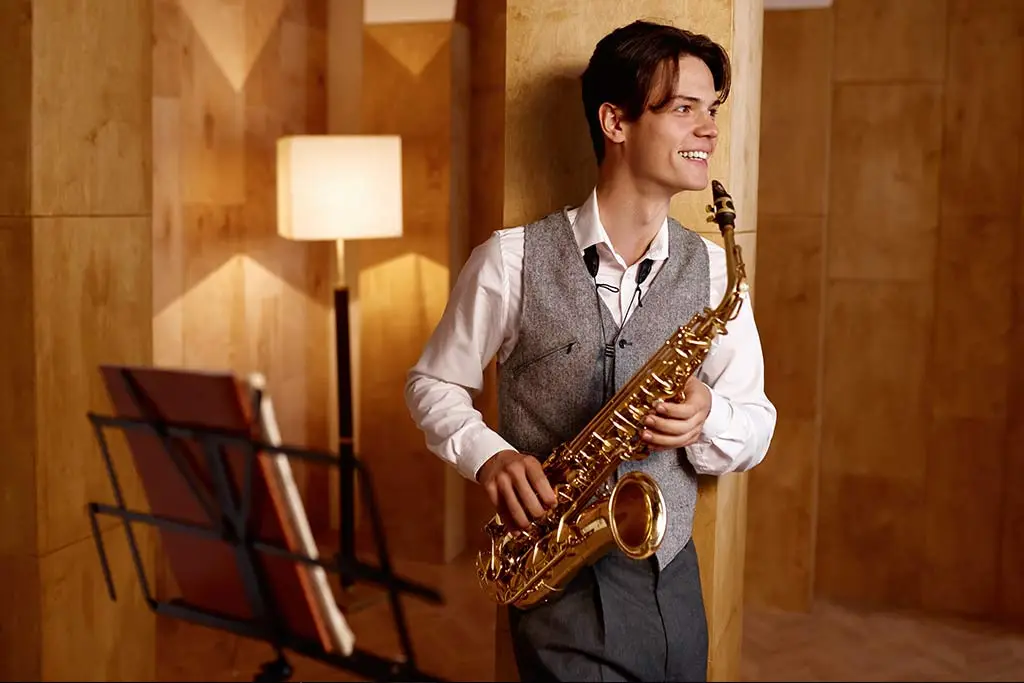 Young man smiling holding a saxophone