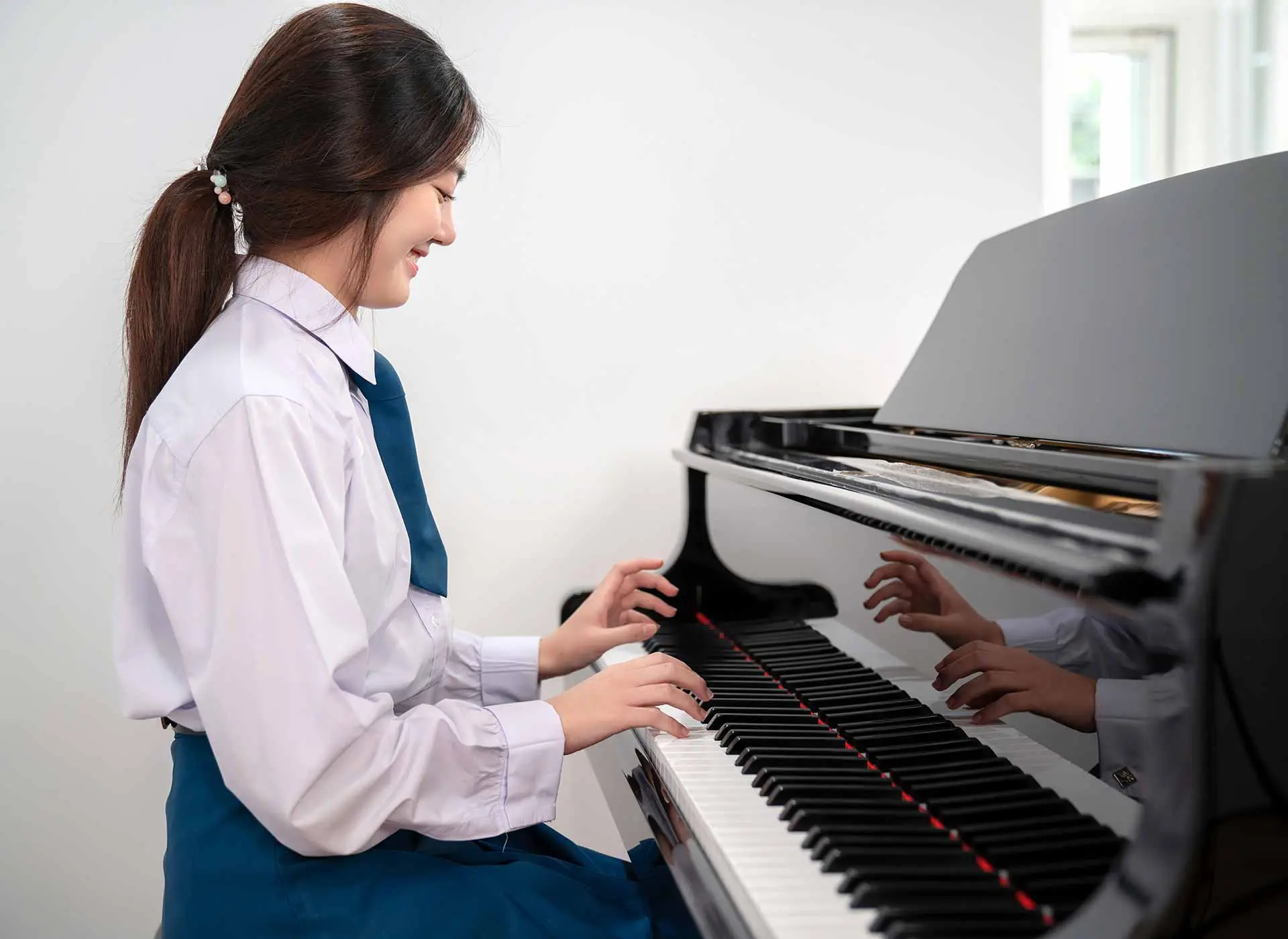 Young woman playing a grand piano in a bright room