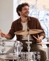 Man playing the drums in a sunlit studio