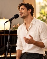 Man singing into a microphone in a warm studio